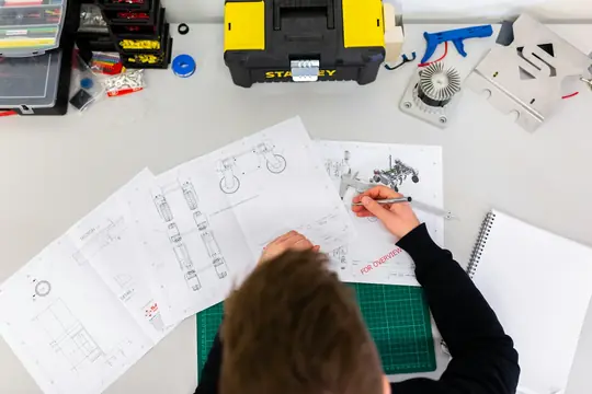 Imagem ilustrativa de um profissional analisando desenhos técnicos em uma bancada
